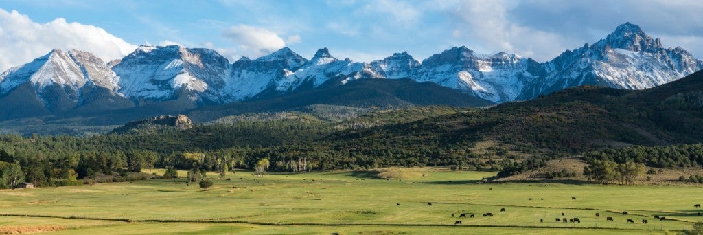 panoramic image of public lands in colorado featuring a mountain range and field