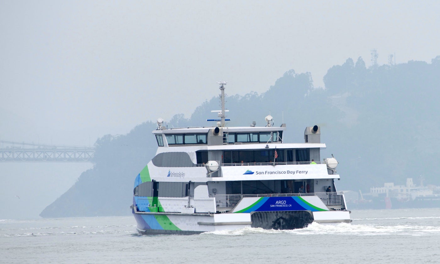 san francisco bay ferry sails across foggy waters with an island in the background