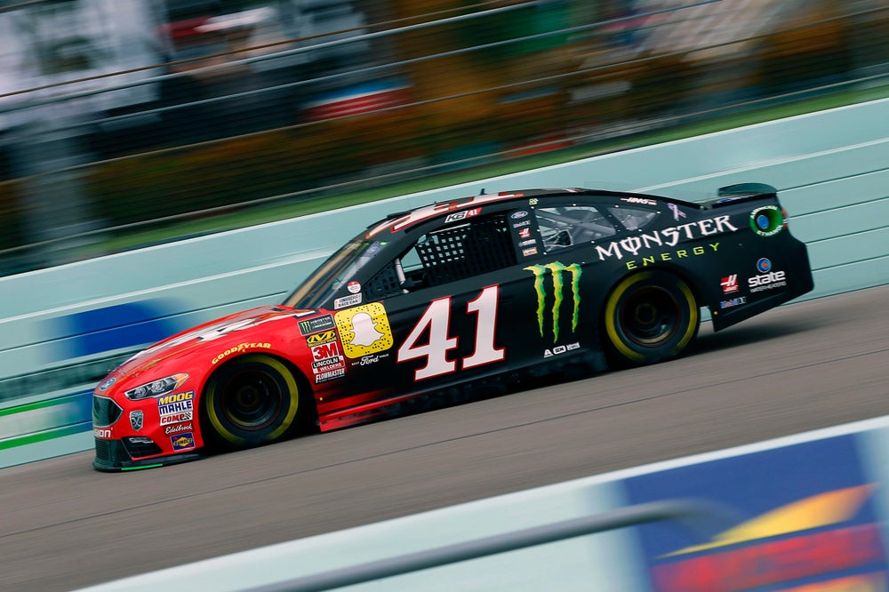 Red and black race car speeding down track with blurred background 