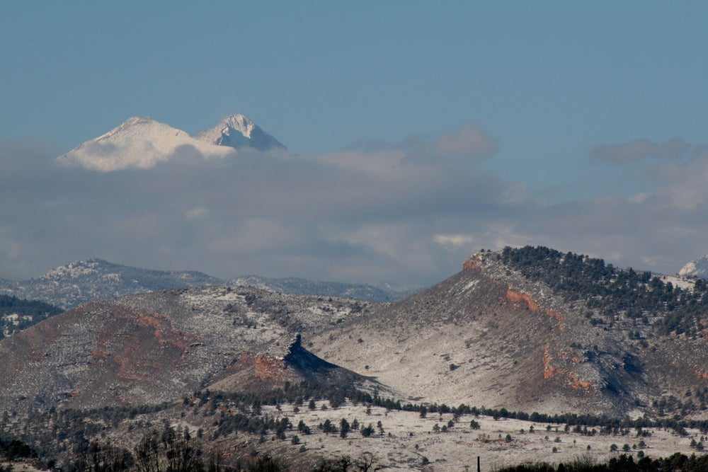 clouds hovering in blue sky over snow-frosted mountains in colorado