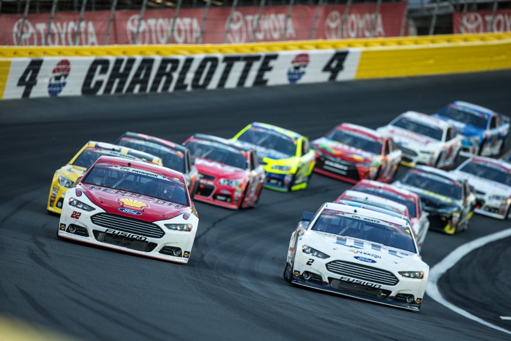 Several multicolored race cars on Charlotte's angled home track