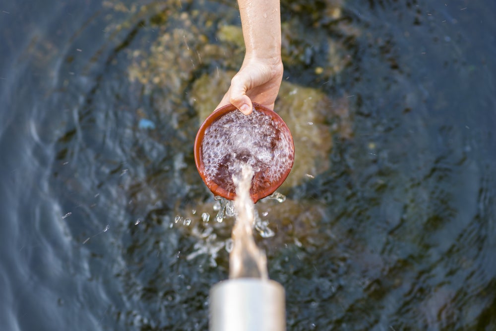 aerial view of water spout pouring water into brown bowl held by person off screen