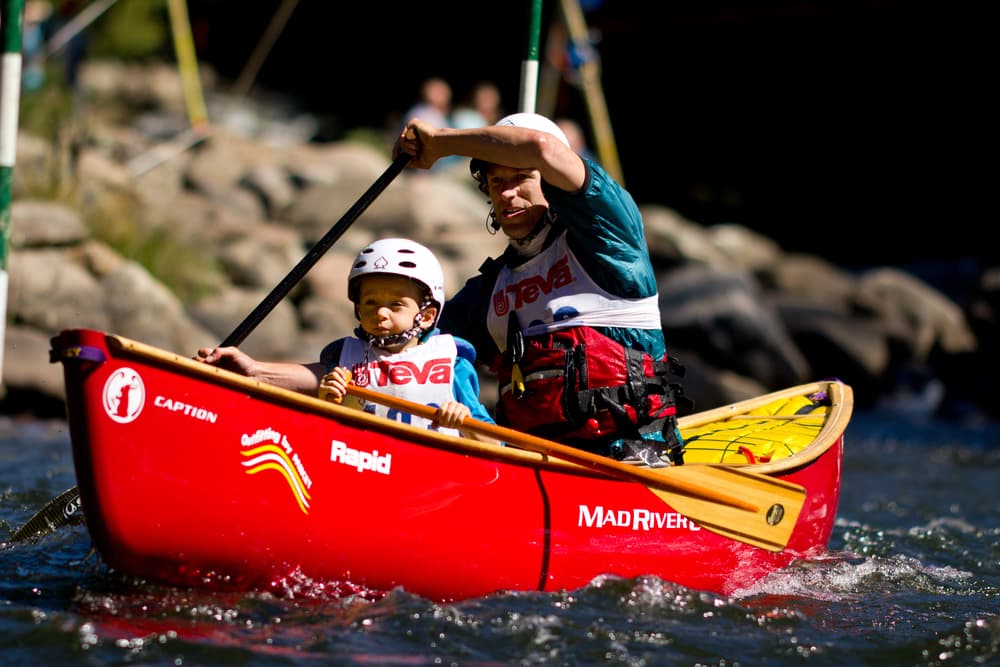 father and young child team paddling in a red canoe during an adventure race