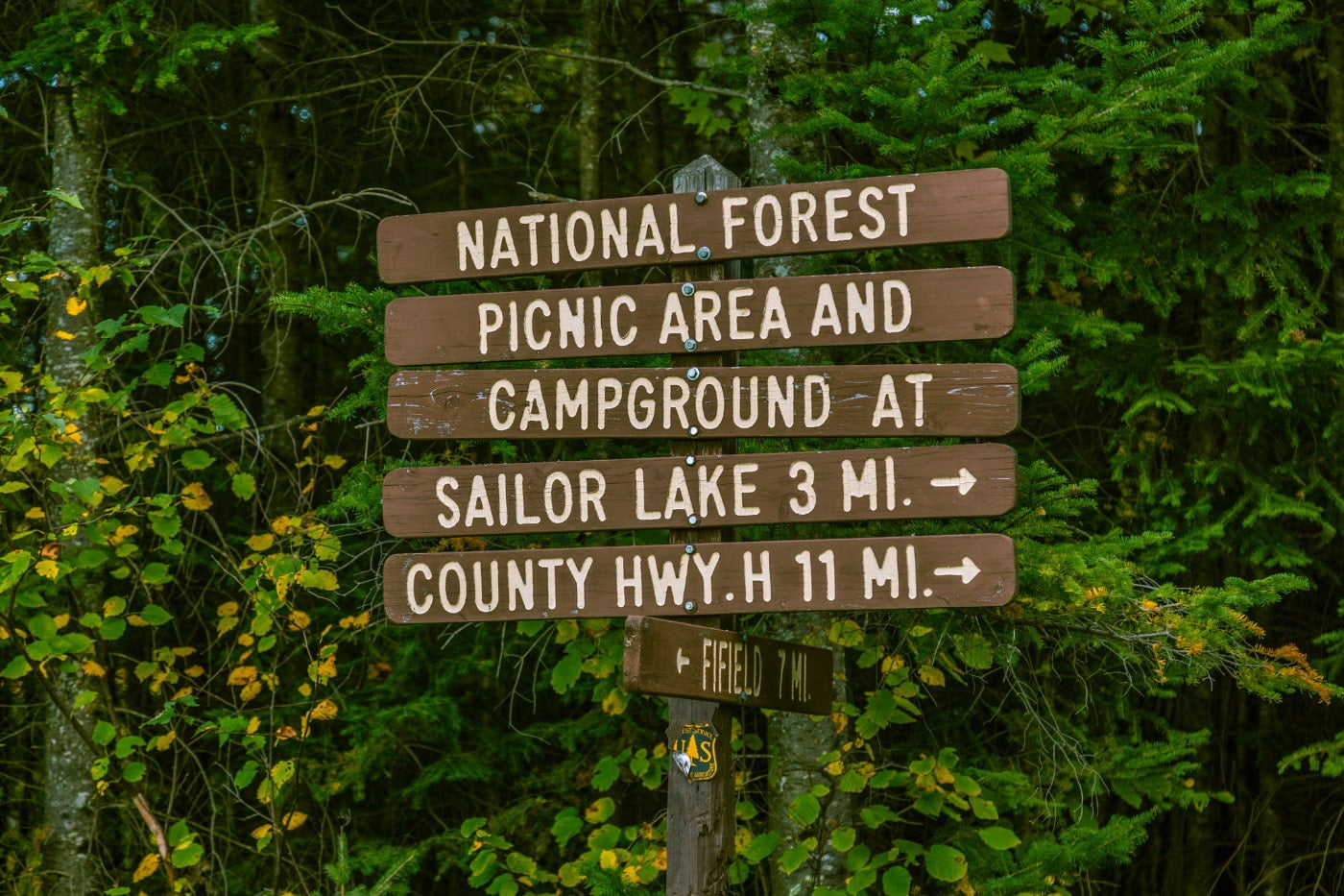 a sign with separate planks of wood pointing toward various Chequamegon-Nicolet National Forest landmarks