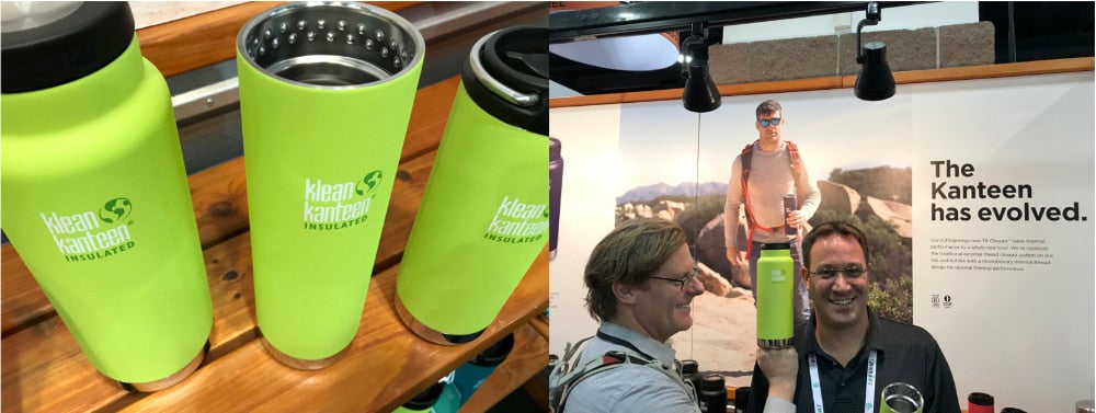 three klean kanteen insulated water bottles stand in a line, one with out a top, and a man holds a water bottle near the head of another man at a convention booth