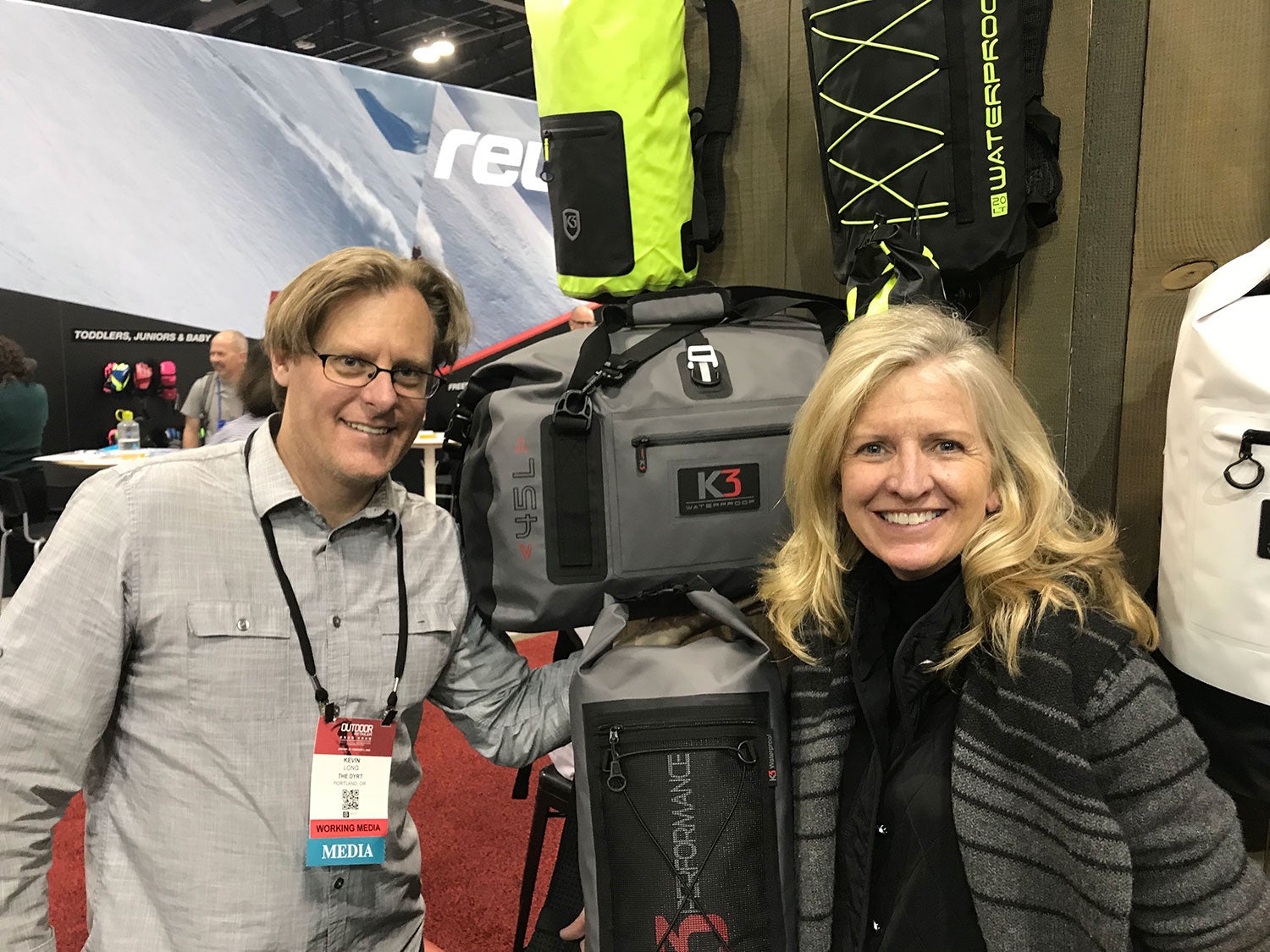 man and woman posing for photo with waterproof duffel bag at outdoor retailer booth