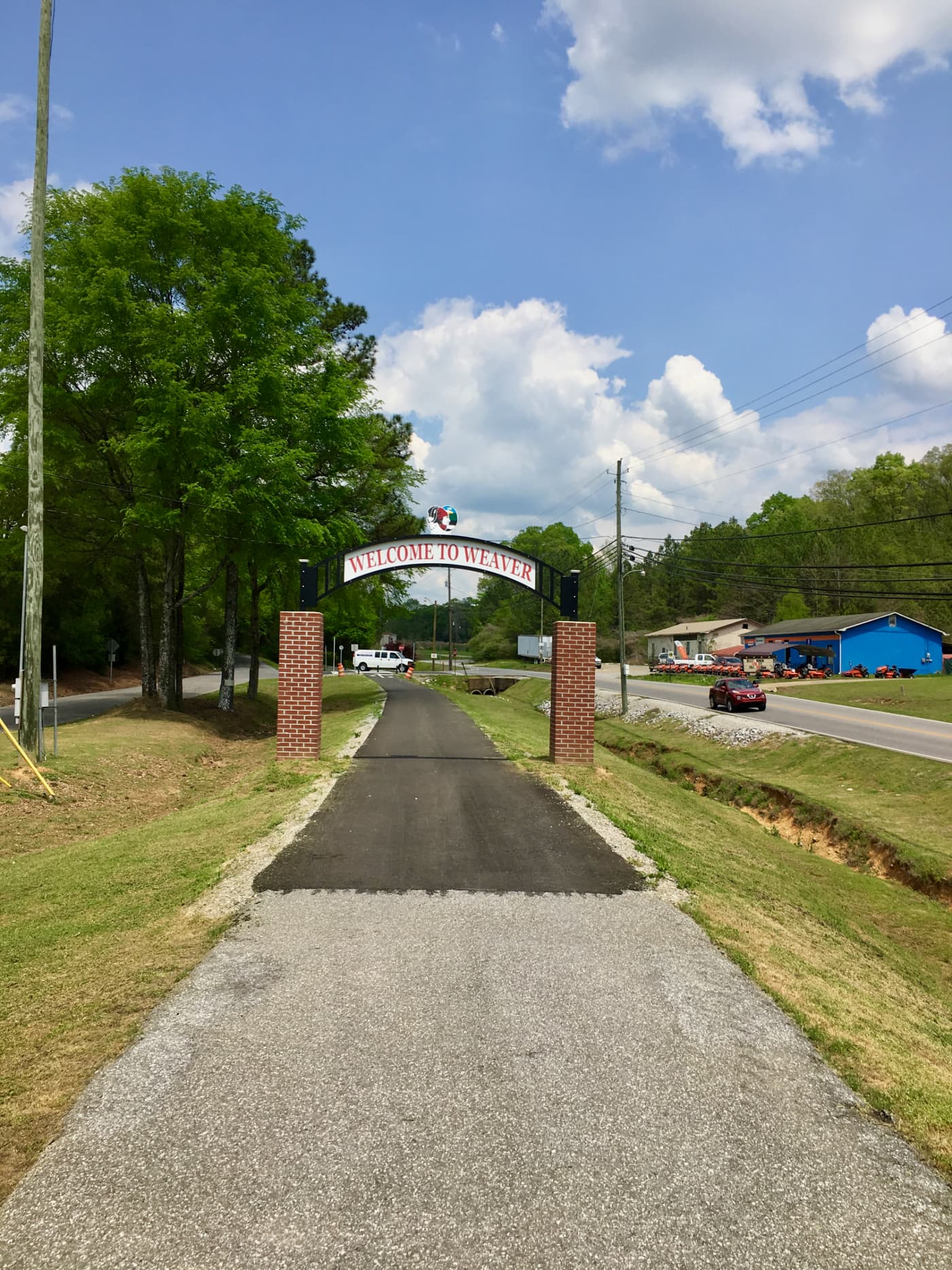 Image of the rail trail with a sign saying "Welcome to Weaver" on brick pillars.