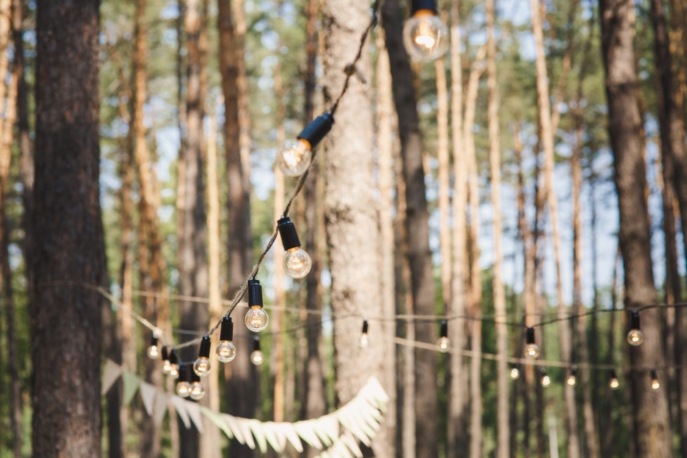 string lights and a flag banner hung to trees in the woods.