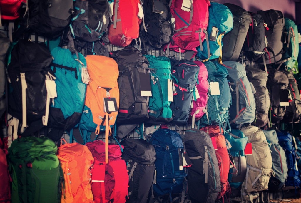 Rows of hanging backpacks in a camping gear rental store