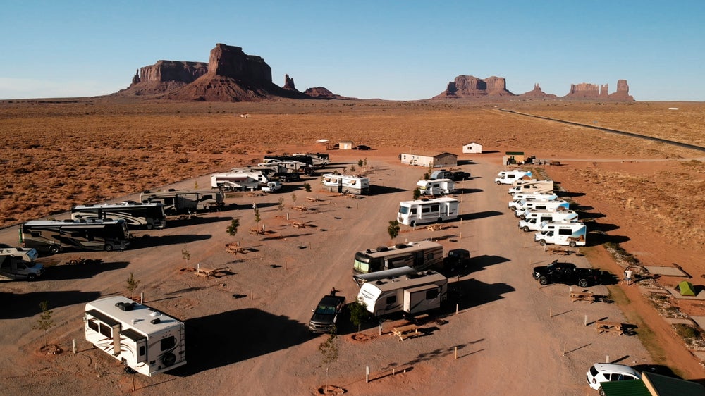 an RV parking lot full of RVs in a desert setting with rocky buttes in the background