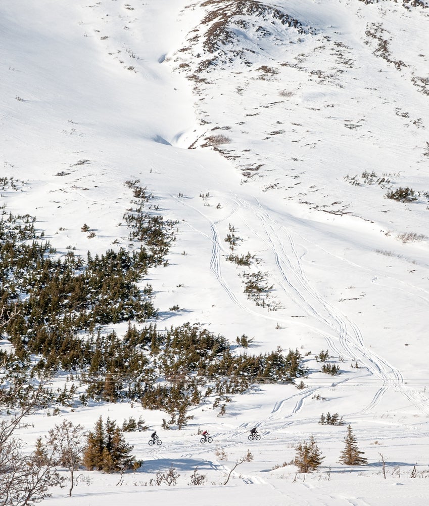 Fat bike trails visible from aerial view of snowy mountainside in Chugach, Alaska