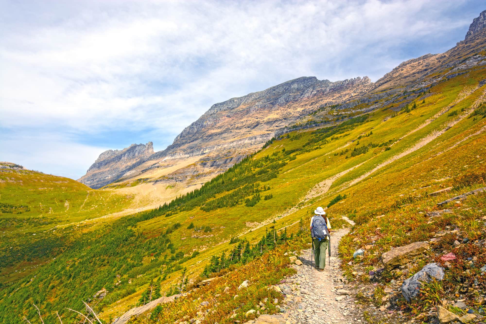 a hiker walks up a rocky trail in glacier national park in montana