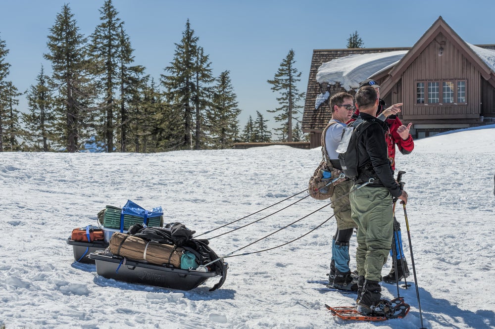 snowshoers towing gear on a sled stop for directions in front of crater lake lodge
