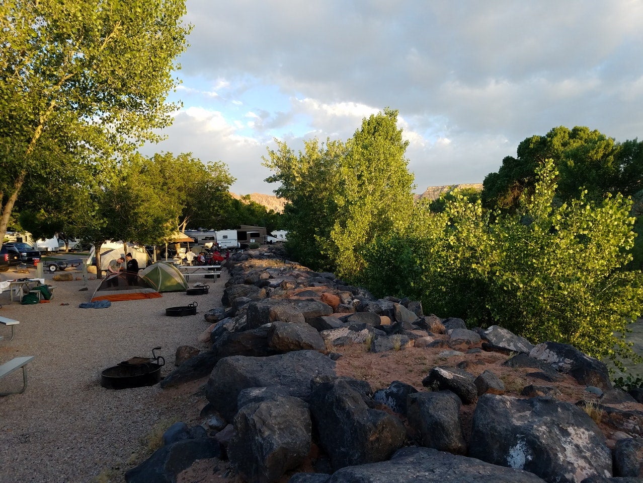 a campground with tents and RVs surrounded by rocks and trees near distant mountains in southern Utah