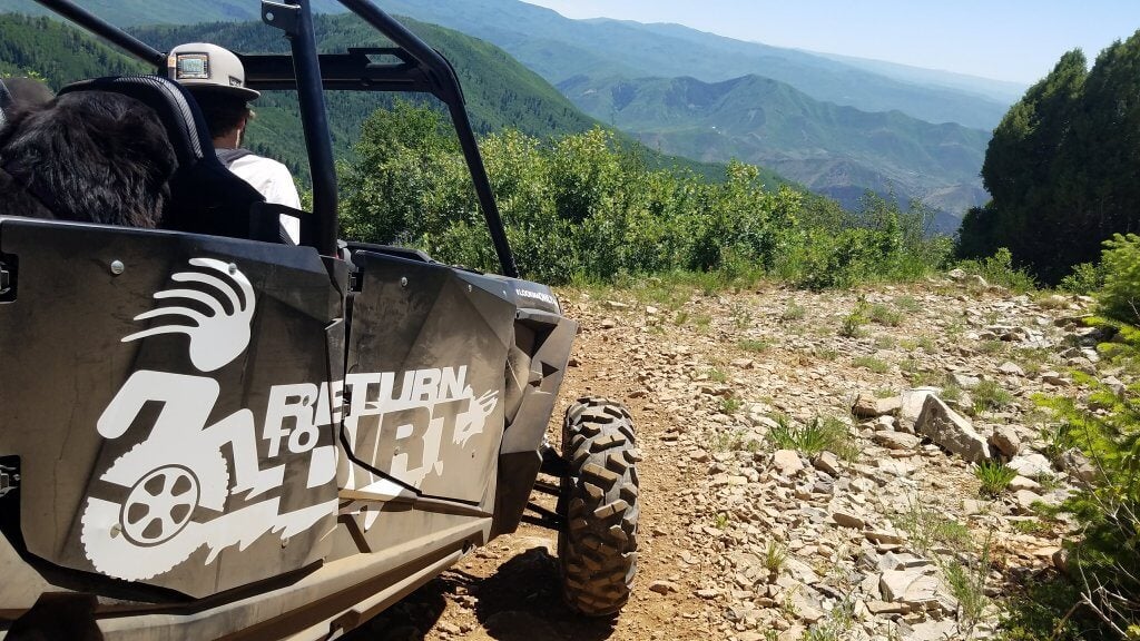 Return To Dirt ATV on rocky road with mountains in background 