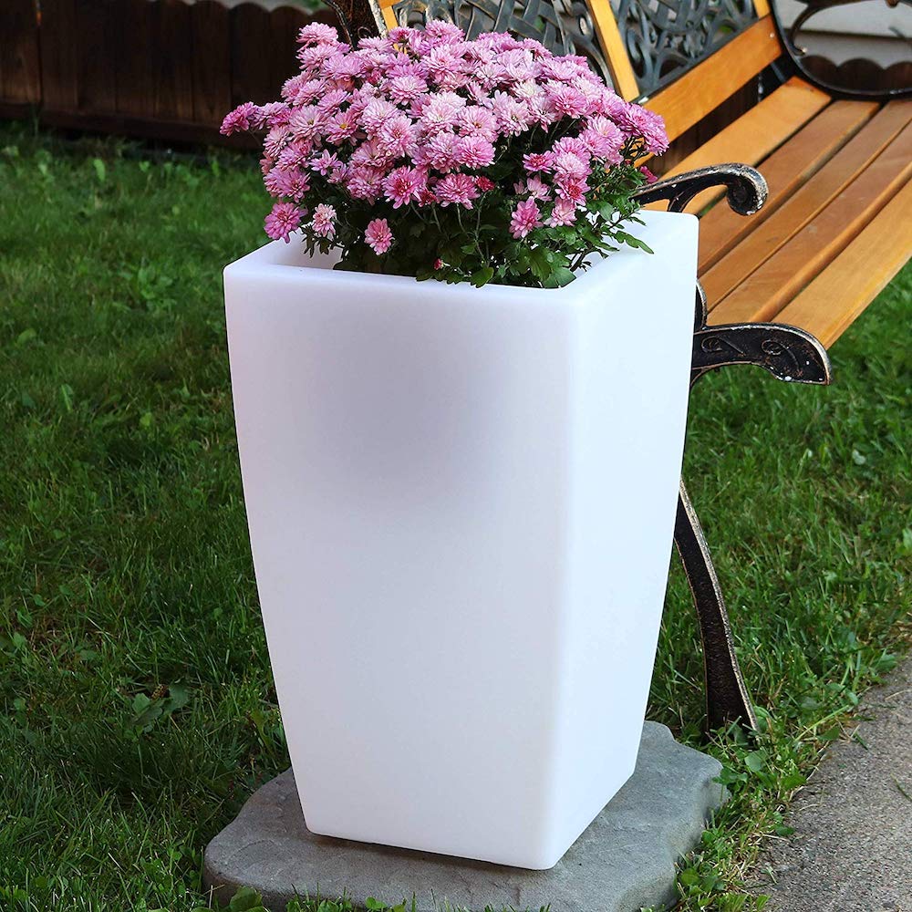 White planter with flowers in it and grass in background