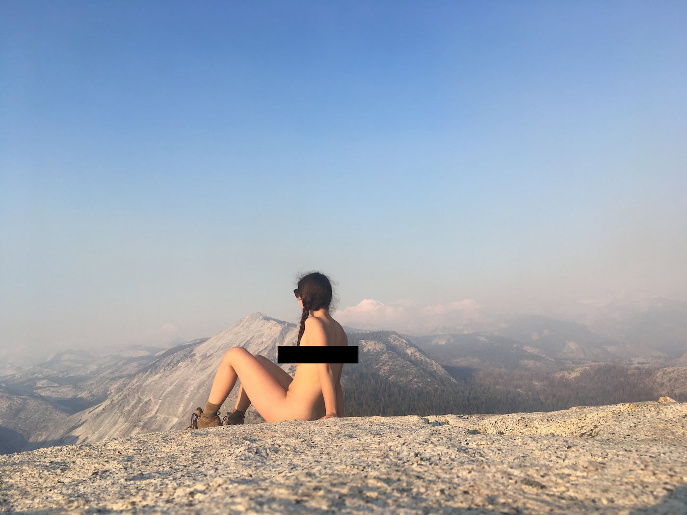 Nude hiker sitting in a mountainous landscape.