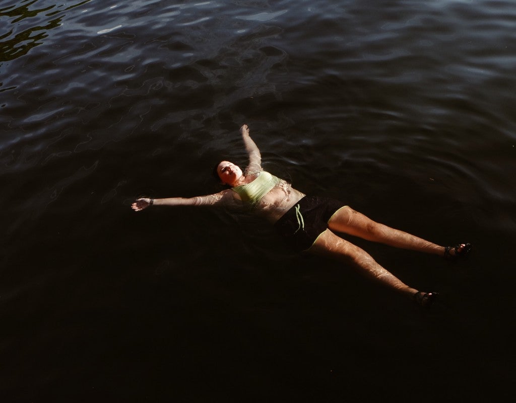Woman floating in a lake in a sports bra and shorts