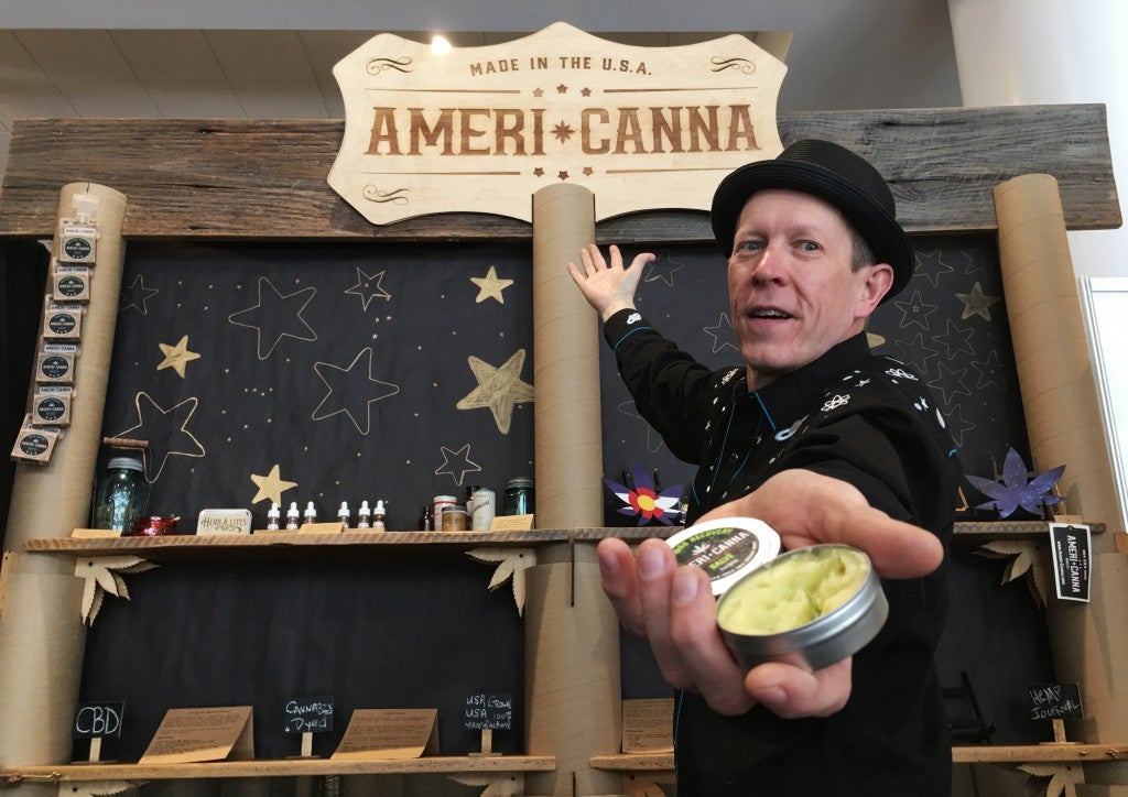 man posing for photo holding americanna cbd cream in front of sales booth