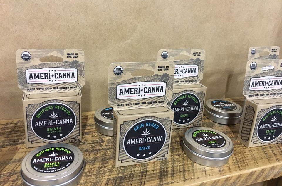 four americanna cbd balm packages on display in boxes and tins