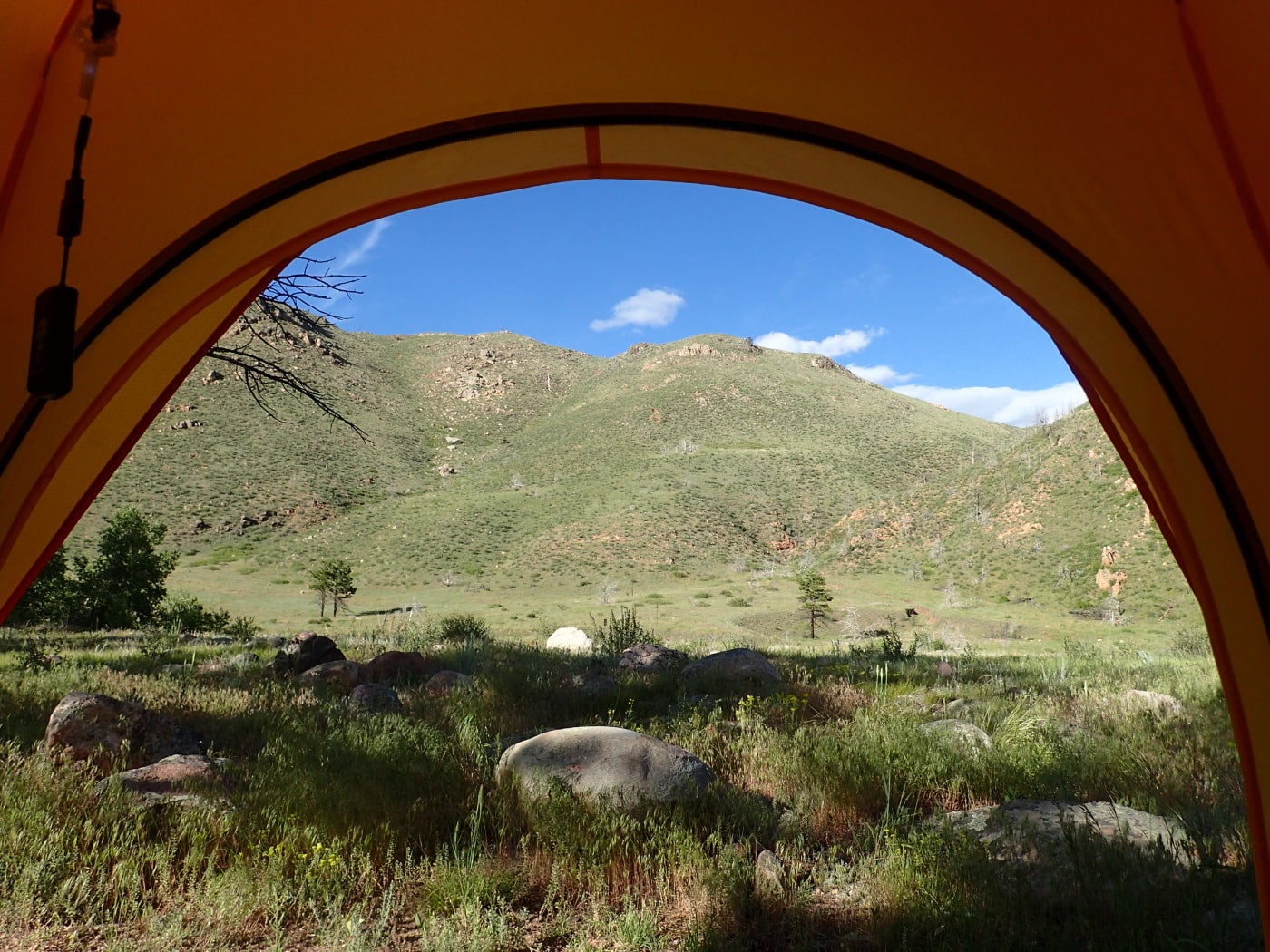 View of a colorado mountain through the door of an orange tent.