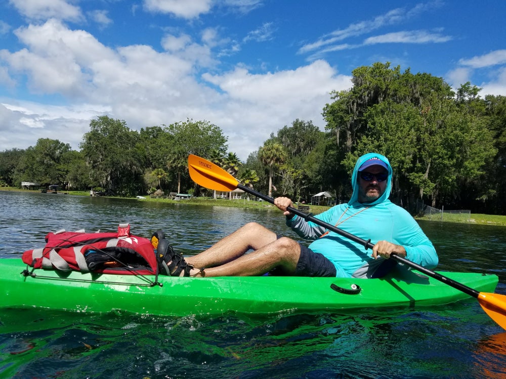 Man sitting in green kayak holding a paddle in a river
