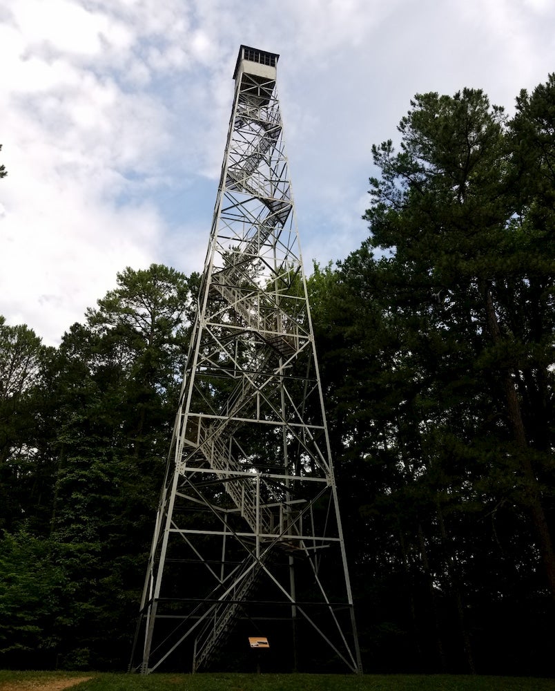 Tall fire tower with zig zag stairs and forest in background