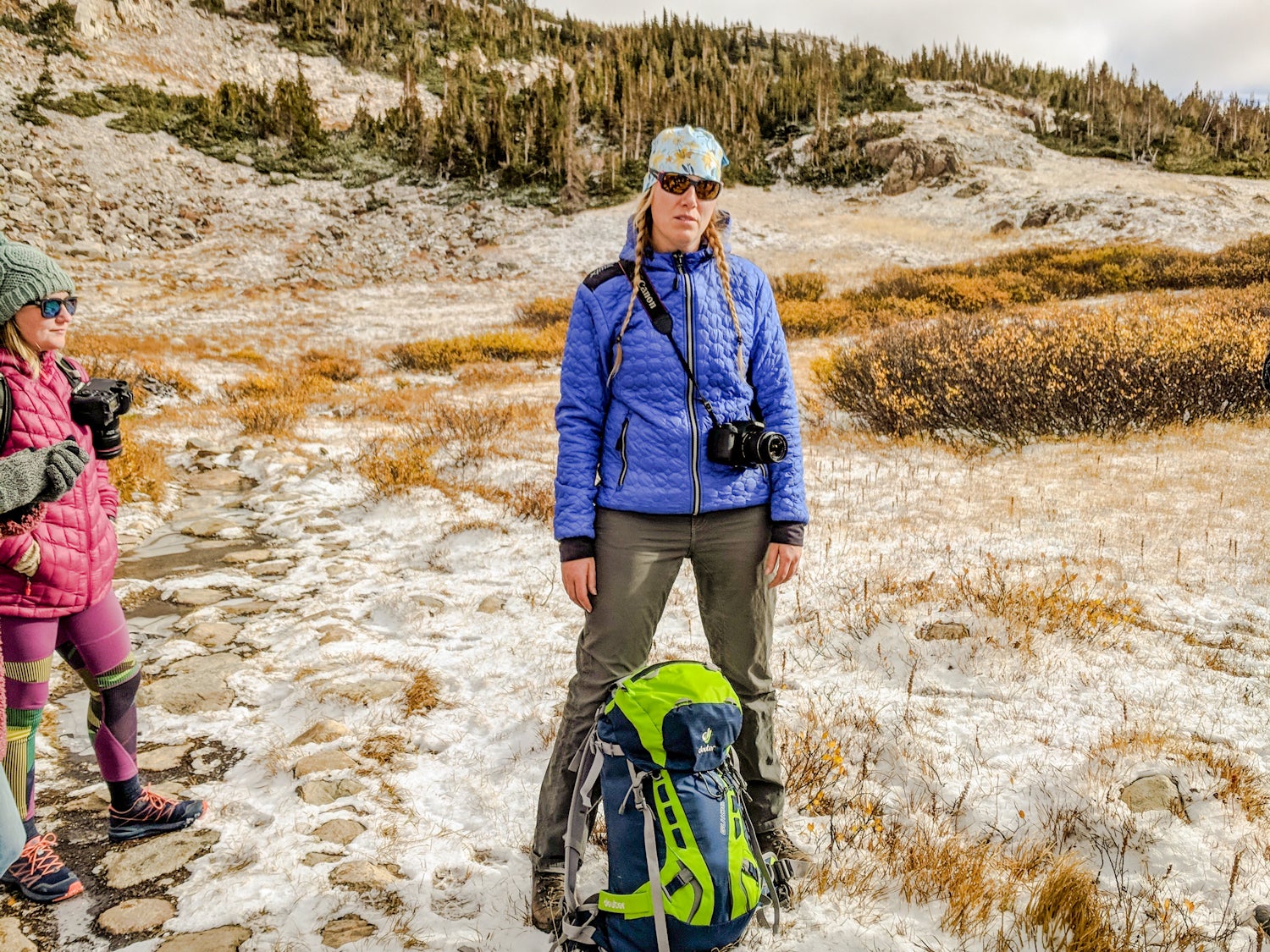 Rebecca Walsh stands with another woman hiker with a backpack in front of her in the backcountry of Wyoming.