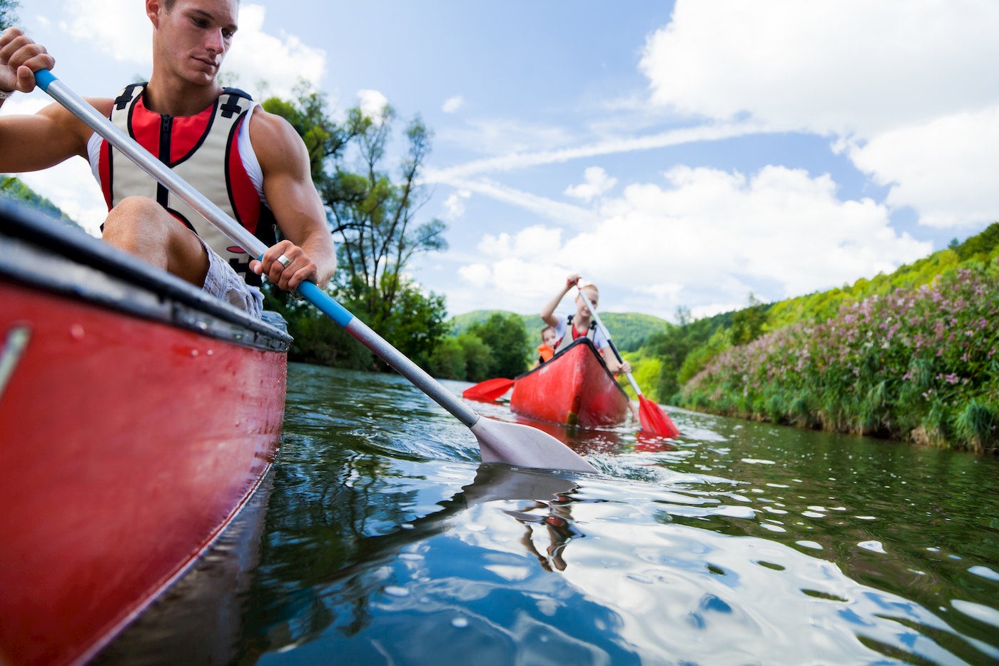 Group paddles a set of canoes wearing life jackets.