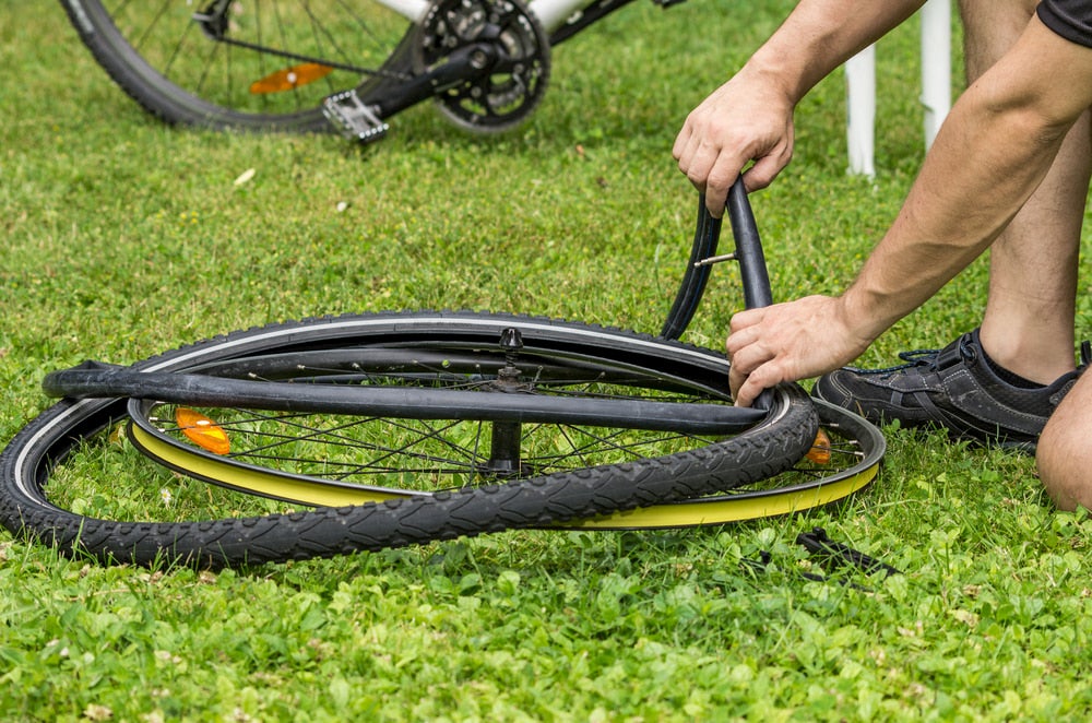 a person changing a bike's flat tire on a lawn.