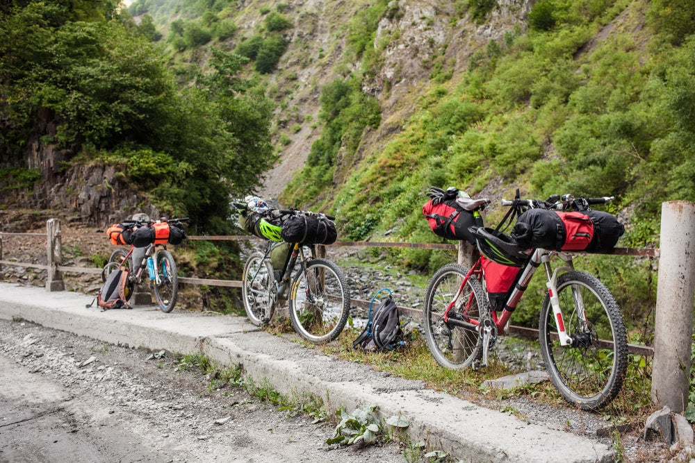 Bikes leaning against a fence with packs strapped to them.