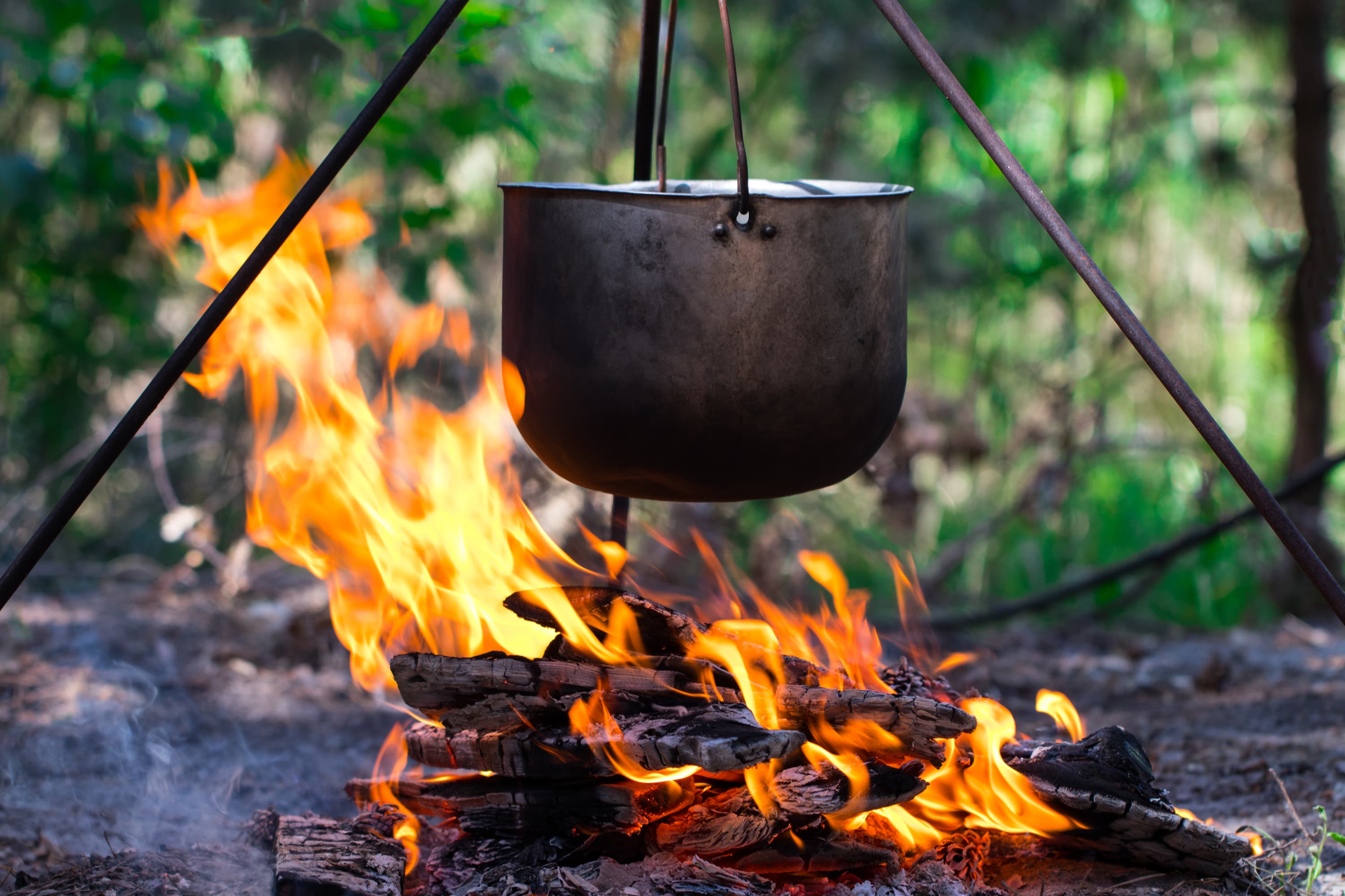 metal pot hanging over campfire