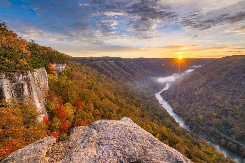 Panoramic view of the New River Gorge with boulder in foreground and sunset in background