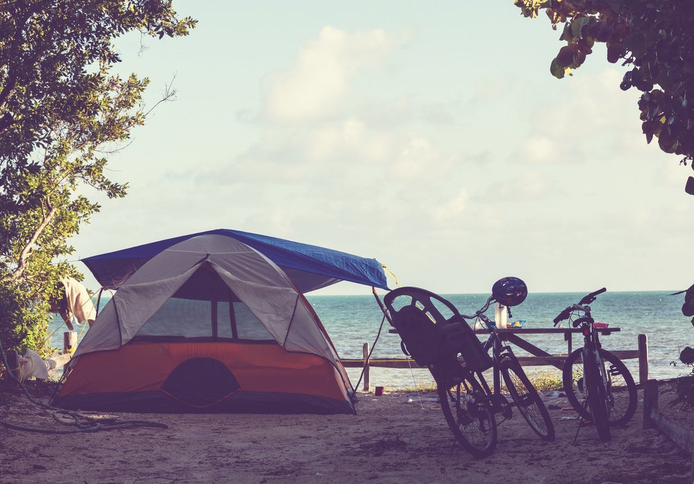 oceanfront campsite with a tent setup besides bike resting on a picnic table