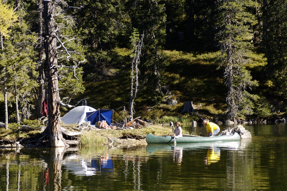 Two people riding their canoe to their campsite.