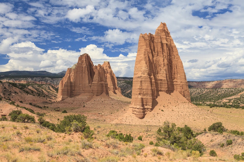 Red rock spires coming up from the ground with blue sky in background 