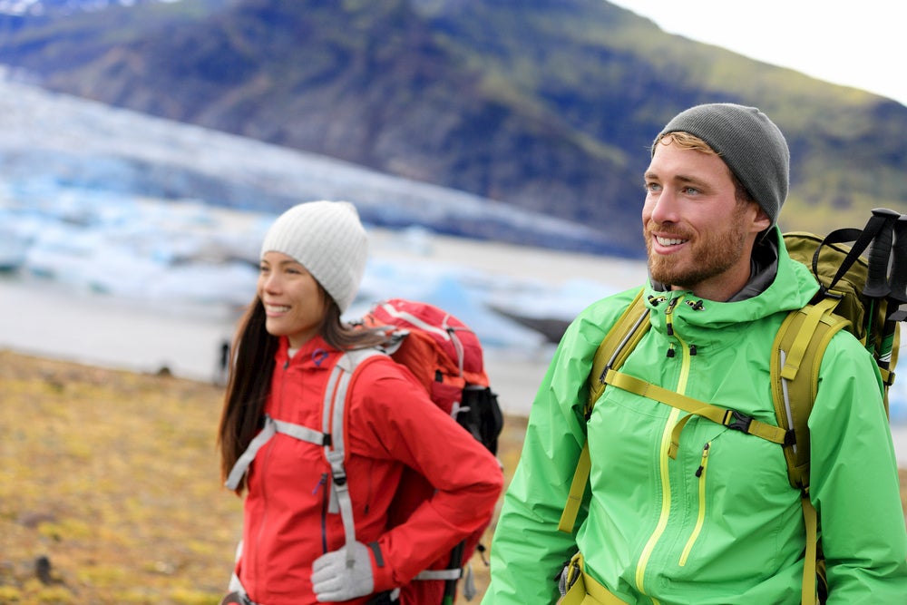 Man and woman hiking with mountains and glacier in background 