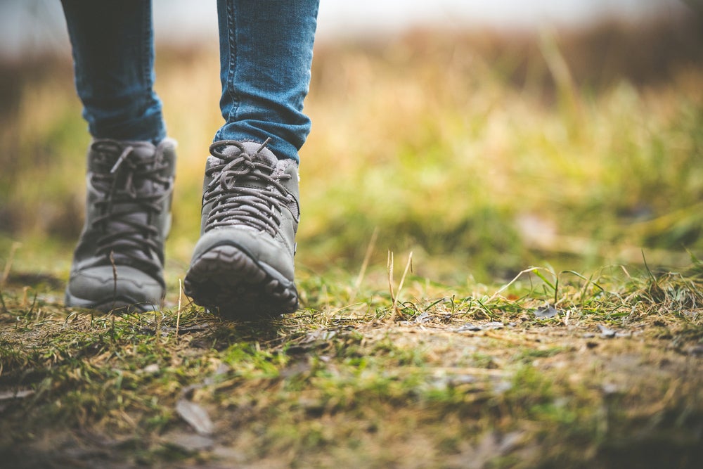 Ground-level view of person in hiking boots walking along a grassy path