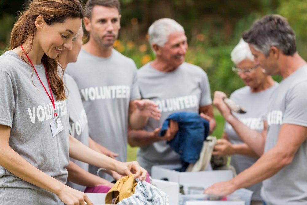 Volunteers smiling and sorting clothes in bins