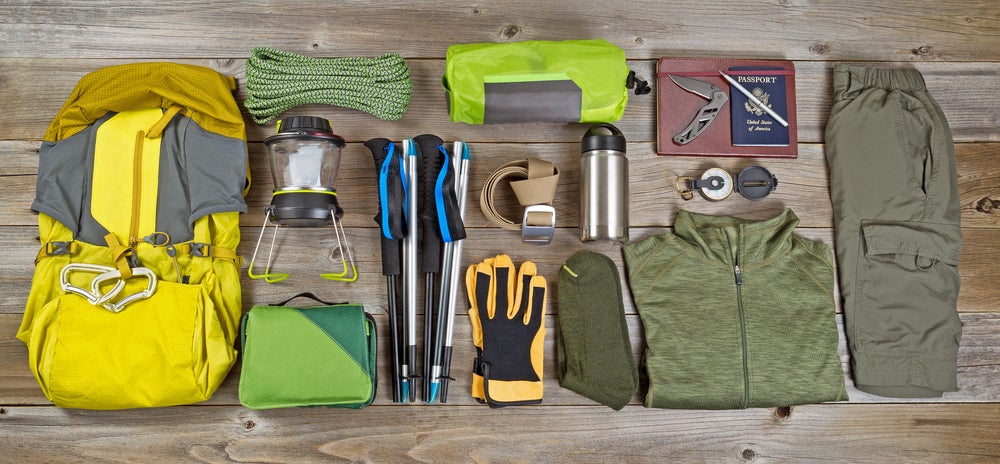 Backpacking gear spread on the floor including backpack, gloves, trekking poles, etc. 
