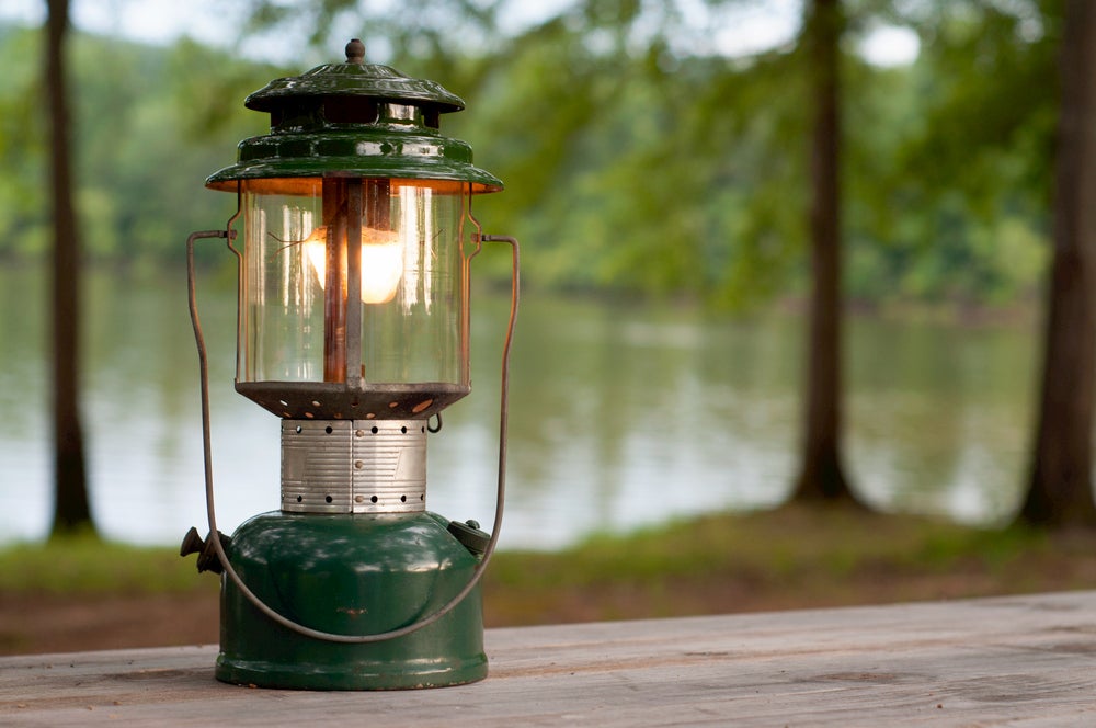 Propane lantern on picnic table with lake in background 