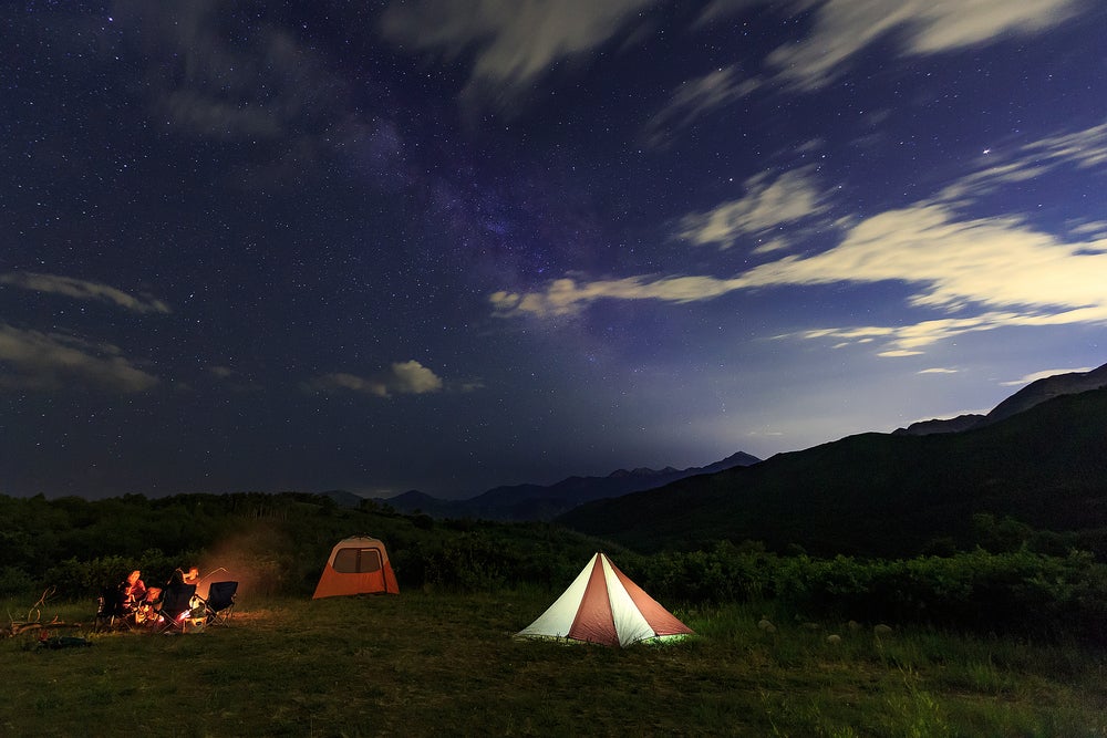 Tent and campfire set up at night within the Wasatch Mountain area of Northern Utah.