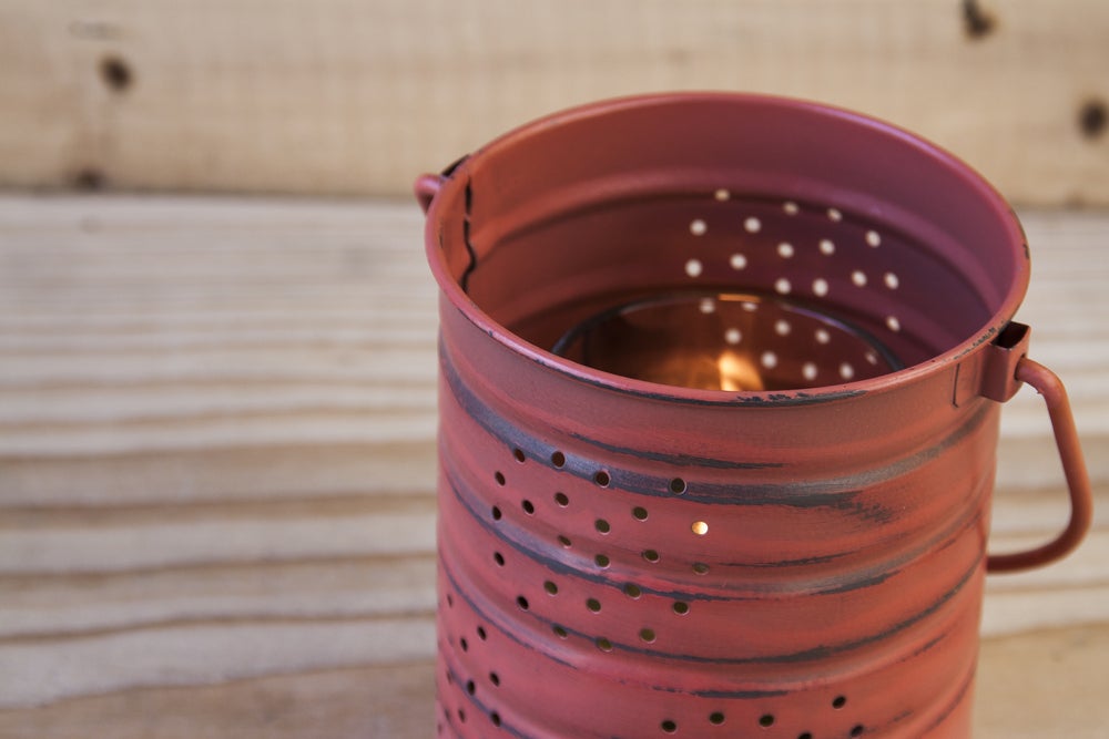 Tin can with candle inside sitting on a table