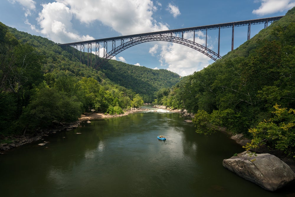 Raft in the middle of a river with bridge in background 