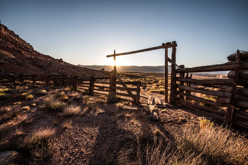 Low sun casts long shadows from wooden dude ranch fencing in arizona farm