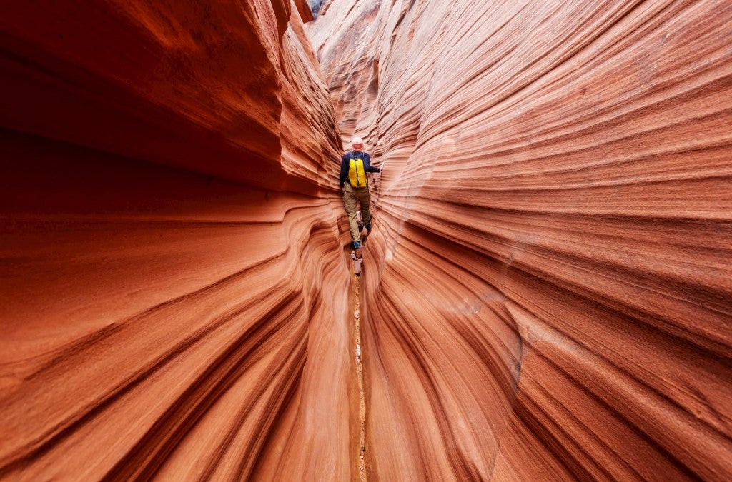 Hiker in the center of a slot canyon in Escalante National Park, Utah.