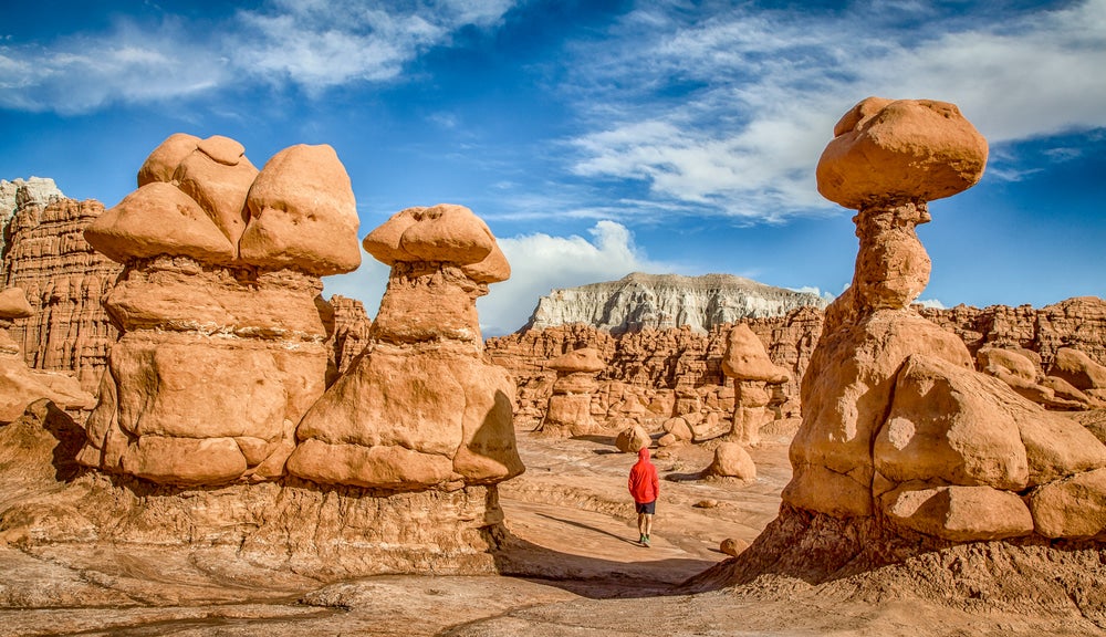 Mushroom-shaped red rocks and man walking along path