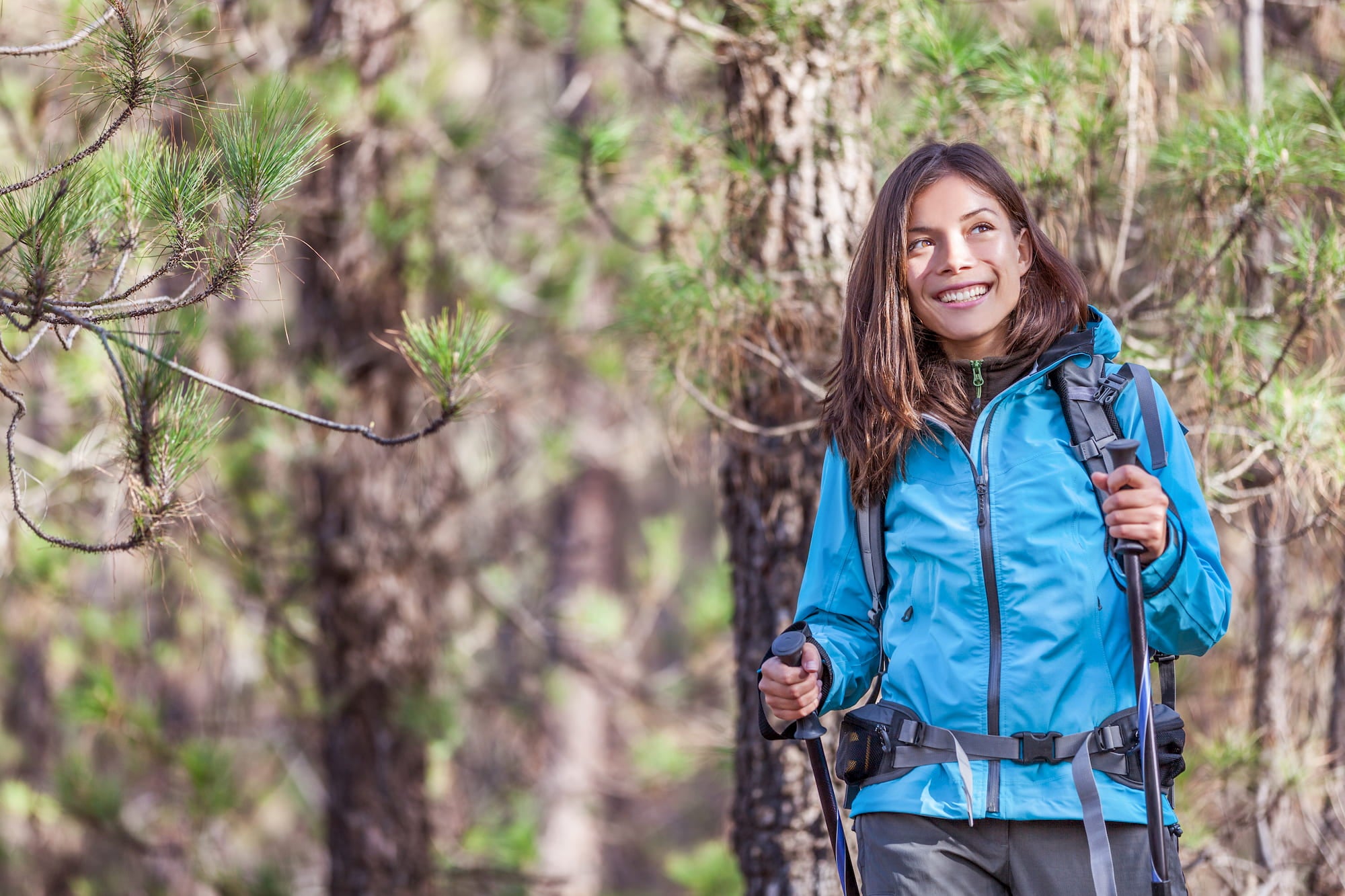 Woman hiking and smiling with trees in background