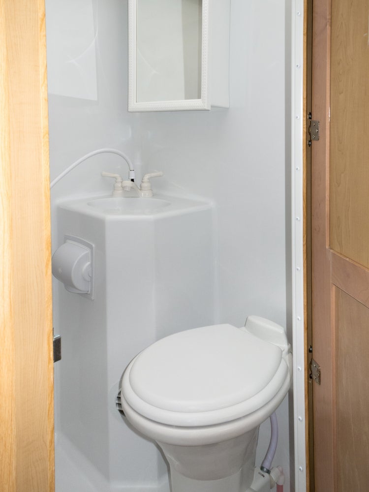 Traditional plastic rv toilet in a white plastic bathroom.