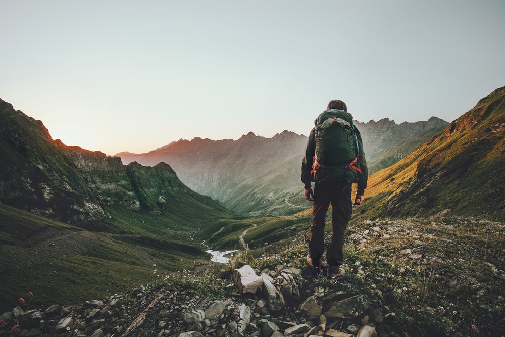 Man backpacking through a mountain valley in the fog at dusk.